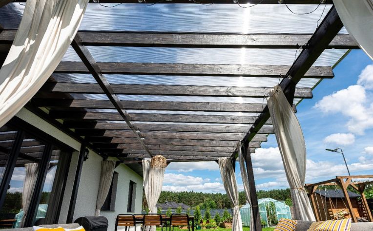 A louvered roof pergola with seating and curtains 